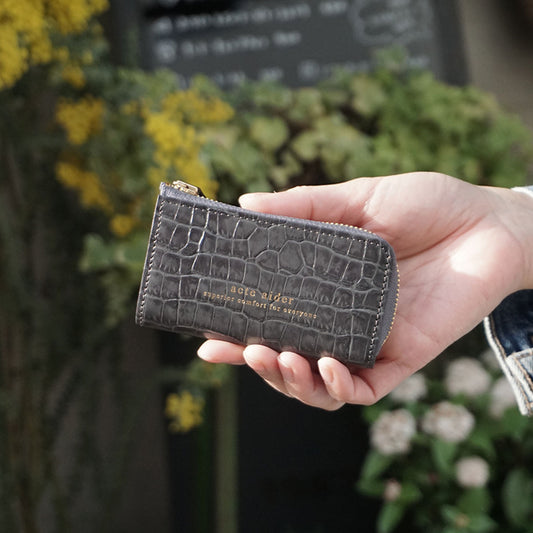 L型ファスナーキーケース クロコ型押しダークグレー アークトエディー 日差しのなか手にするミニ財布