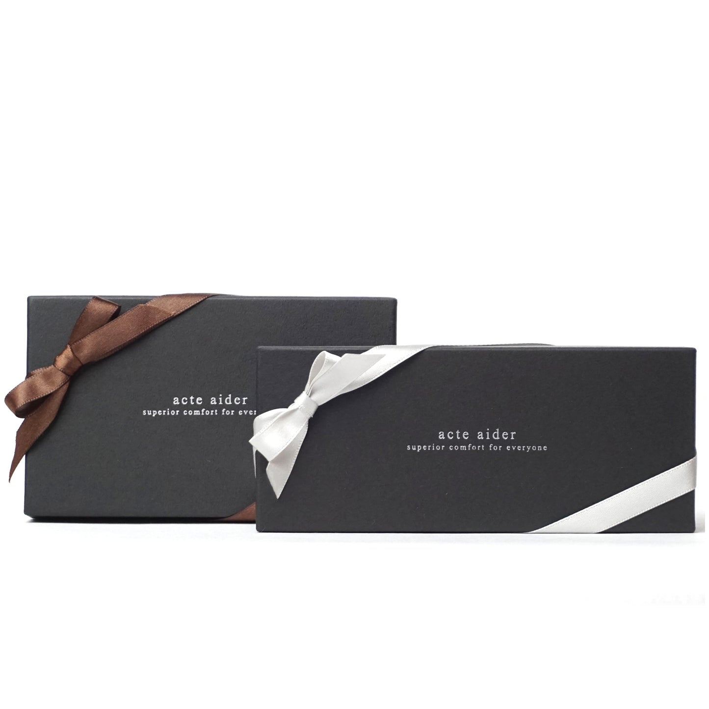 アークトエディーサイズ別パッケージ見本 白い背景に置かれたロゴ入り黒箱2つ それぞれブラウンのリボンとシルバーのリボンがかけられた画像