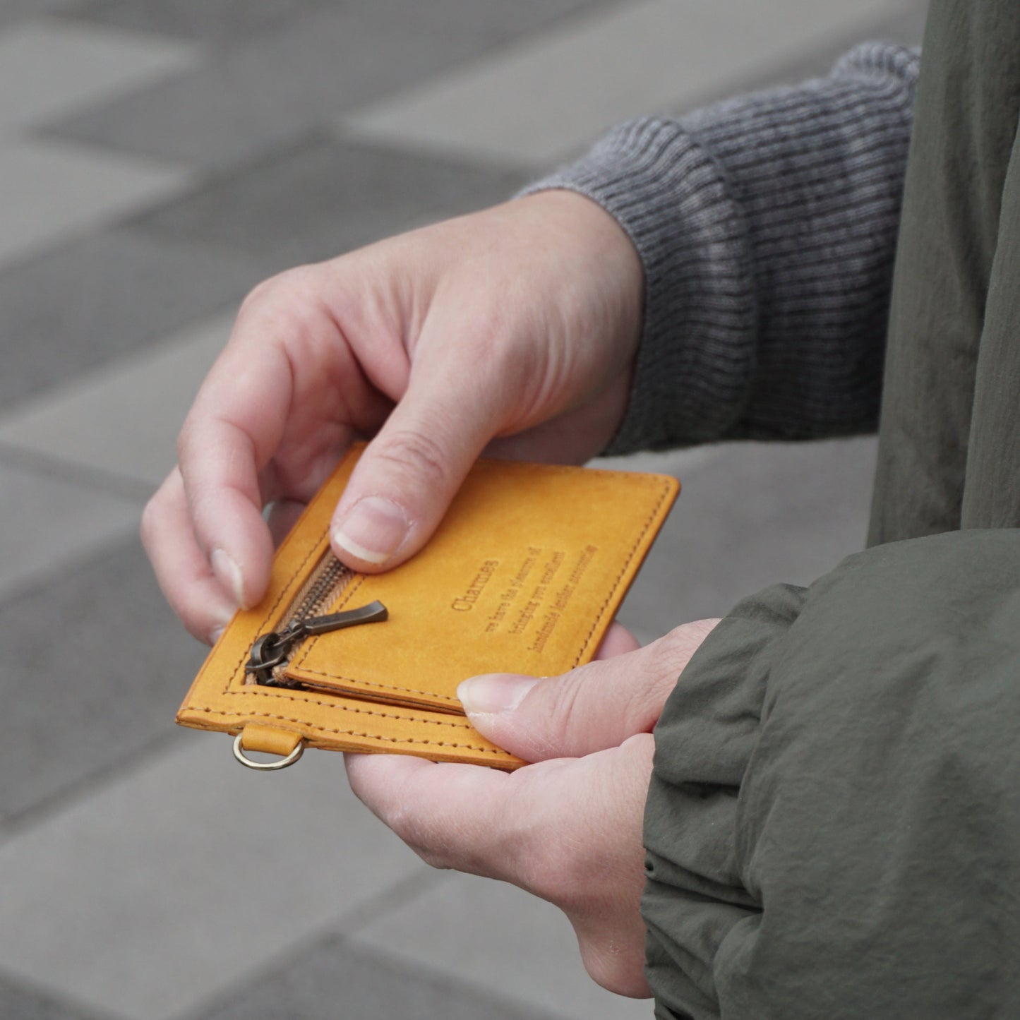 カードケース　マルゴーシリーズ　イエロー　シャルム　駒屋　石畳に立つ女性が両手でカードケース持つ様子　女性の手元のアップ画像